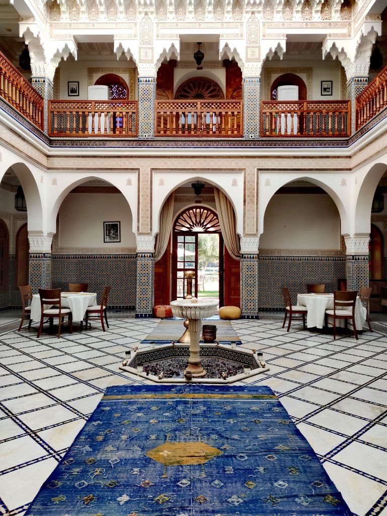 Traditional Moroccan riad courtyard with arched arcades, zellige tilework and a central fountain