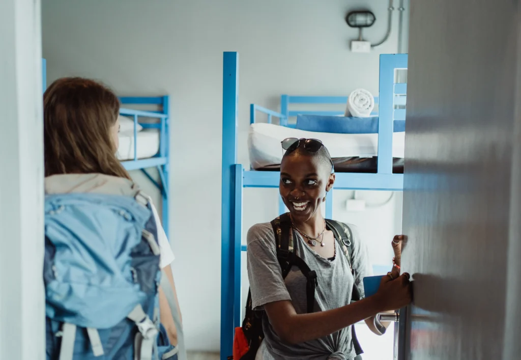 Travelers in a budget hostel dorm with bunk beds